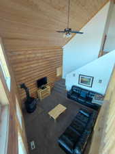 Living room featuring rustic walls, wood ceiling, high vaulted ceiling, and a ceiling fan