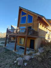 Back of house with a deck, a patio area, and log exterior