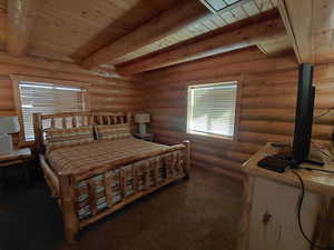 Bedroom featuring rustic walls, a wooden ceiling with exposed beams, and dark colored carpet