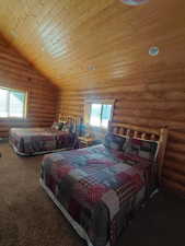 Carpeted bedroom with rustic walls, wood ceiling, and lofted ceiling