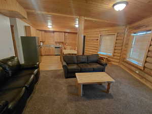 Living room featuring wood ceiling, carpet, and rustic walls