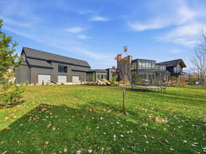 View of grassy yard with a trampoline and a balcony