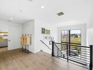 Corridor featuring an upstairs landing, light wood-style floors, and recessed lighting
