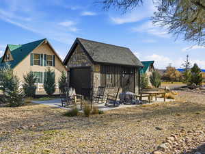 View of front of house with stone siding, an outbuilding, roof with shingles, and board and batten siding