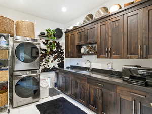 Washroom featuring stacked washer / dryer and light tile patterned floors