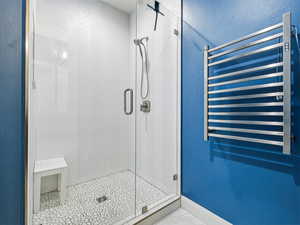 Full bath with radiator heating unit, a shower stall, and a textured wall