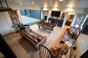 Living area featuring wet bar, light wood-type flooring, and recessed lighting