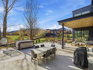 View of patio / terrace with outdoor dining space, a hot tub, a mountain view, grilling area, and an outdoor living space
