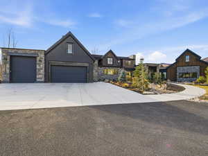 View of front facade with stone siding, concrete driveway, and an attached garage