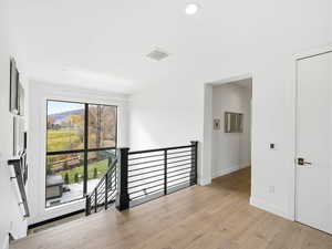 Hall with an upstairs landing and light wood-type flooring