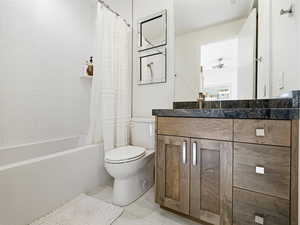 Full bathroom featuring shower / bath combination with curtain, vanity, light tile patterned flooring, and a ceiling fan