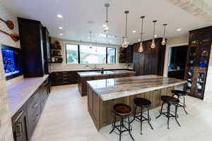 Kitchen with dark brown cabinets, open shelves, pendant lighting, light stone counters, and recessed lighting