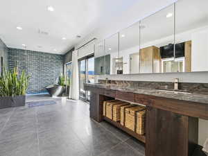 Bathroom with a freestanding bath, double vanity, recessed lighting, and tiled shower