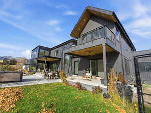 Back of property with a patio, a hot tub, and a yard