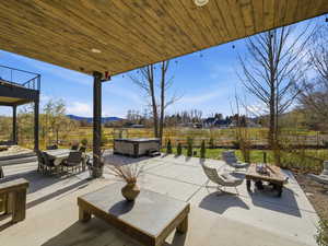 View of patio / terrace featuring a hot tub, a mountain view, outdoor dining area, and a fire pit