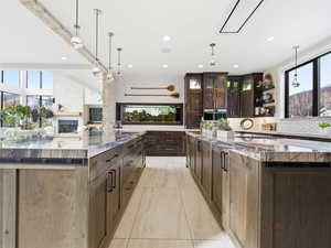 Kitchen with open shelves, dark stone countertops, dark brown cabinets, healthy amount of natural light, and recessed lighting