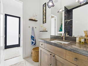Full bathroom with vanity, a tile shower, and light tile patterned floors