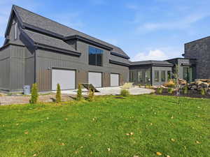 Rear view of property with a lawn, a shingled roof, and a sunroom