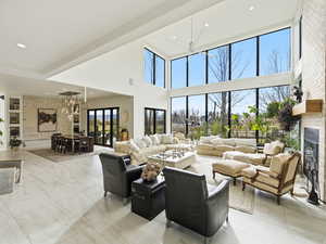 Living area with a glass covered fireplace, a high ceiling, a chandelier, recessed lighting, and ceiling fan