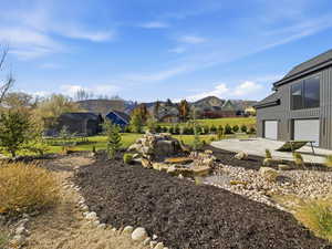 View of yard featuring a trampoline, a patio, a garage, and concrete driveway