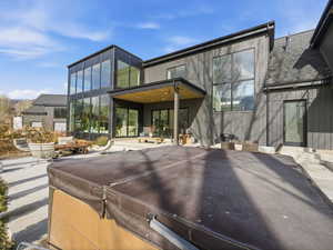 Rear view of property with a patio, a shingled roof, and a hot tub
