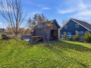 Rear view of house with board and batten siding, an outbuilding, and a yard
