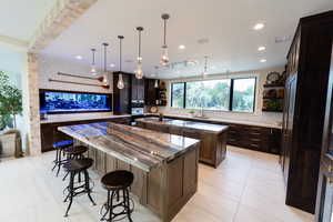 Kitchen with open shelves, dark brown cabinets, dark stone countertops, pendant lighting, and recessed lighting