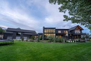 Rear view of house with a lawn, a trampoline, a patio area, and a balcony