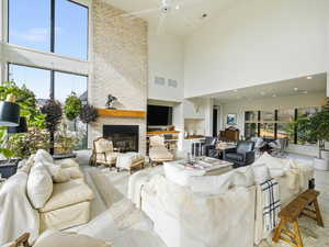 Living room featuring a high ceiling, a ceiling fan, and a fireplace