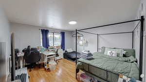 Bedroom featuring light wood-style floors, a desk, and a textured ceiling
