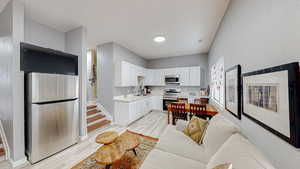 Kitchen with light countertops, stainless steel appliances, white cabinetry, and light wood-type flooring