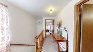 Hallway with an upstairs landing and light carpet