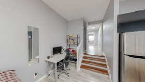 Home office with light wood-style floors and a textured wall