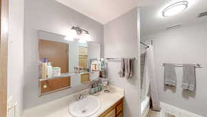 Full bathroom featuring vanity, shower / bath combo, and a textured wall