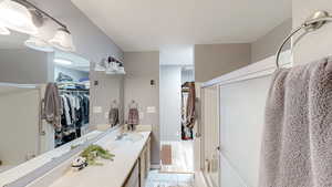 Full bath with vanity, a walk in closet, and shower / bath combination with glass door