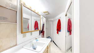 Bathroom featuring vanity, a textured ceiling, curtained shower, light floors, and a textured wall