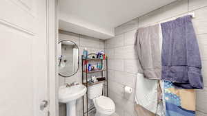 Half bathroom featuring tile walls and toilet