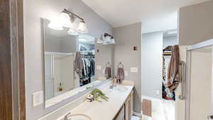Full bathroom with a spacious closet, double vanity, a shower stall, and light wood-type flooring
