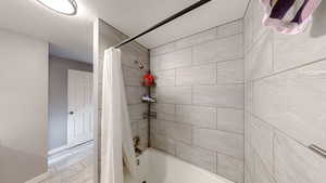 Full bath featuring shower / tub combo with curtain, wood finish floors, and a textured ceiling