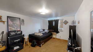 Bedroom with a textured ceiling and light colored carpet