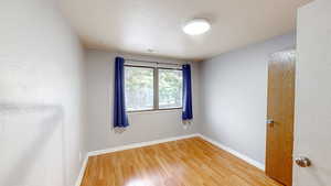 Unfurnished room featuring light wood-style flooring and a textured ceiling