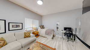 Bedroom with light wood-type flooring, a desk, and lofted ceiling