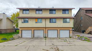 Rear view of house with brick siding, driveway, and an attached garage