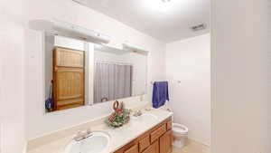 Full bathroom featuring double vanity, a shower with shower curtain, and a textured wall