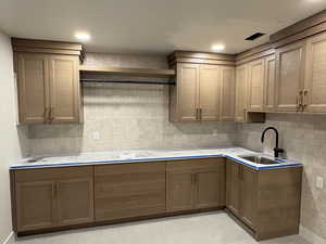 Kitchen with backsplash, light countertops, wood finish cabinetry, light tile patterned flooring, and recessed lighting