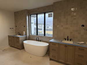 Bathroom featuring tile walls, two vanities, and a freestanding bath