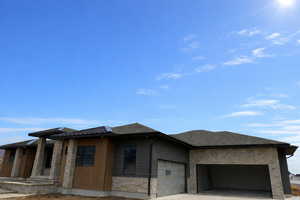 View of front facade featuring stone siding, an attached garage, and concrete driveway