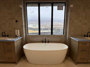 Bathroom featuring vanity, tile walls, and a freestanding bath