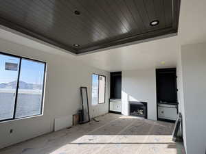Unfurnished living room with wooden ceiling and a tray ceiling