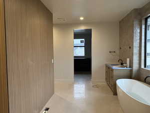 Full bath featuring a freestanding bath, tile walls, recessed lighting, and vanity